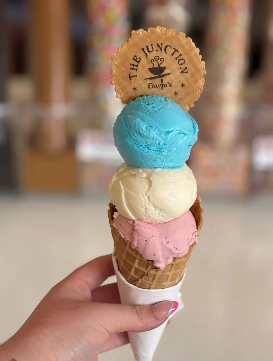 Three scoops of gelato in a waffle cone with a Junction wafer