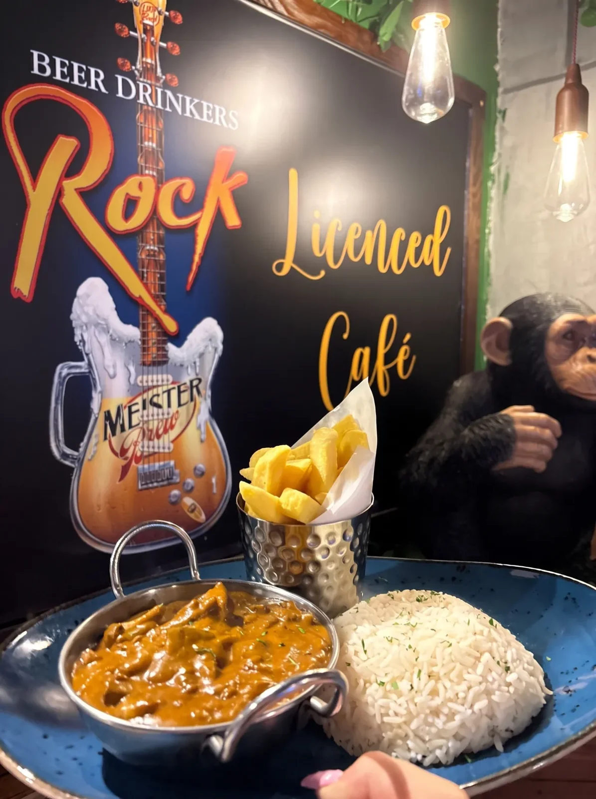 Chicken curry with rice and chips under the Rock Licenced Café sign
