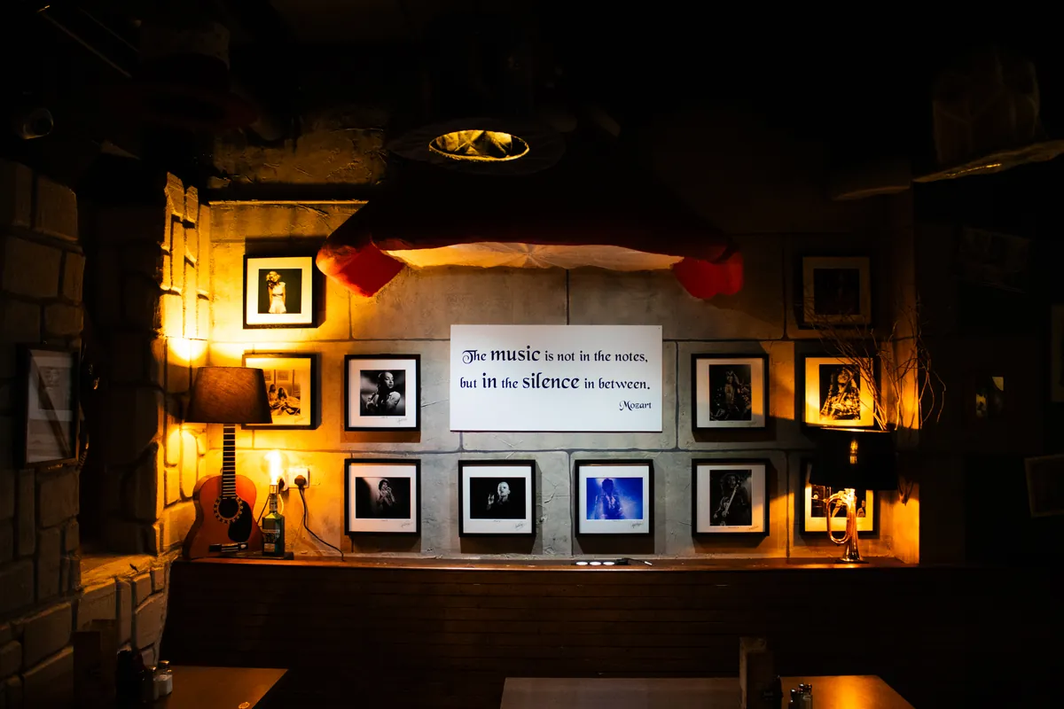 Framed photographs under a music quote, lit warm