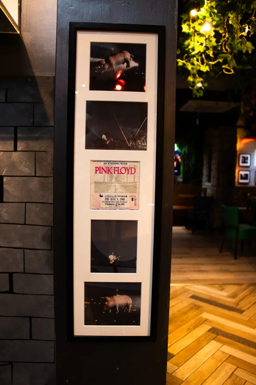 A tall frame of Pink Floyd photographs and a concert ticket, wrapped around a pillar.