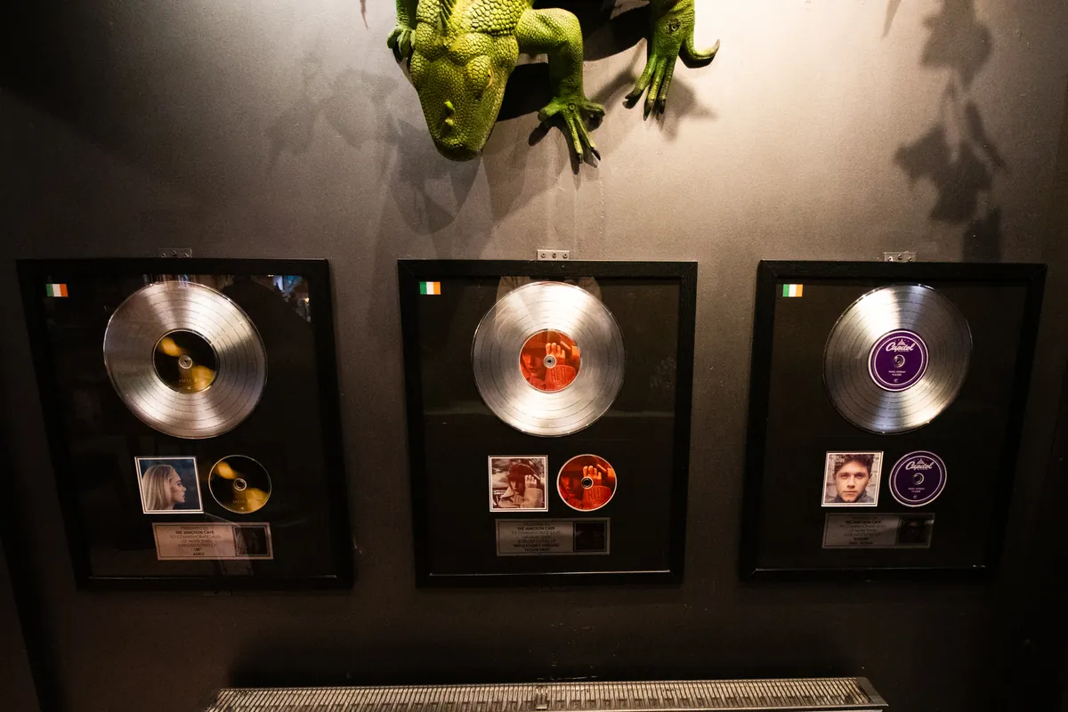 Framed platinum and gold discs under a green dragon that keeps watch over the tables.