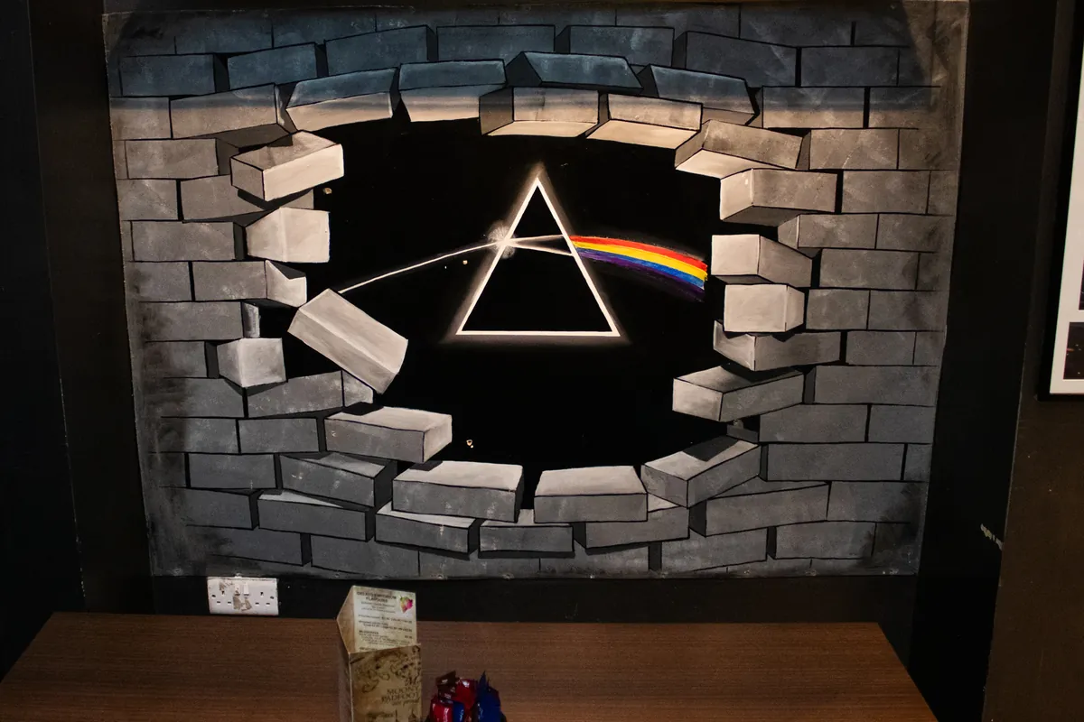 The Dark Side of the Moon prism, painted breaking through a brick wall.