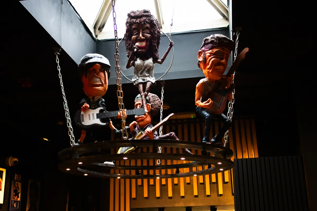 Tina Turner, Bruce Springsteen, Keith Richards (Rolling Stones) and Angus Young (AC/DC), on a stage hanging from the ceiling.